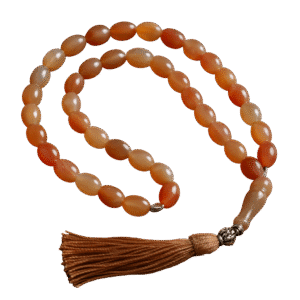 Handcrafted Haqeeq tasbeeh with polished gemstone beads and a decorative tassel, arranged neatly on a soft background