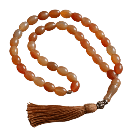 Handcrafted Haqeeq tasbeeh with polished gemstone beads and a decorative tassel, arranged neatly on a soft background