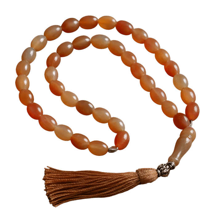 Handcrafted Haqeeq tasbeeh with polished gemstone beads and a decorative tassel, arranged neatly on a soft background